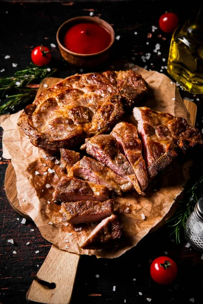 stock image Delicious grilled pork steak with tomato sauce and rosemary. Against a dark background. High quality photo