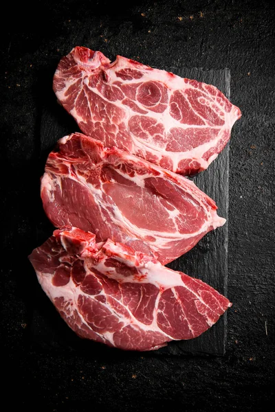 Čerstvý Nevařený Vepřový Steak Kamenné Desce Černém Pozadí Kvalitní Fotografie — Stock fotografie
