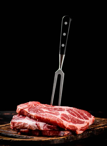 用叉子把生猪排放在切菜板上 在一个黑色的背景 高质量的照片 — 图库照片