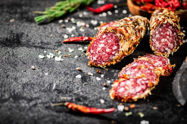 stock image Salami sausage with rosemary and dried chili pepper pods. On a black background. High quality photo