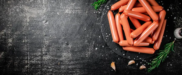 stock image Sausages boiled on a stone board with spices and rosemary. On a black background. High quality photo