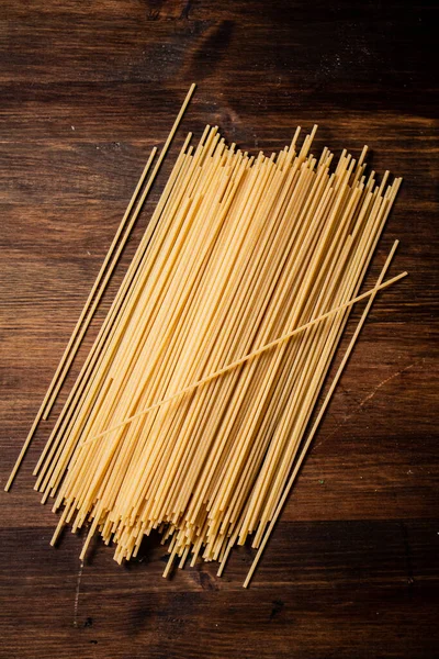 テーブルの上にスパゲティがたくさん乾いている 木製の背景に 高品質の写真 — ストック写真