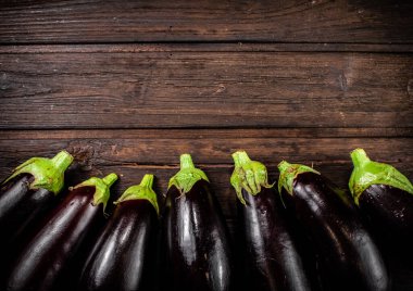 Fresh eggplants are in a row on the table. On a wooden background. High quality photo