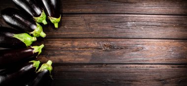 Fresh eggplants are in a row on the table. On a wooden background. High quality photo