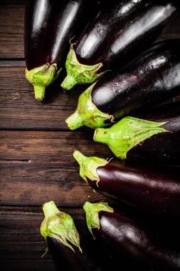 Fresh eggplants are in a row on the table. On a wooden background. High quality photo