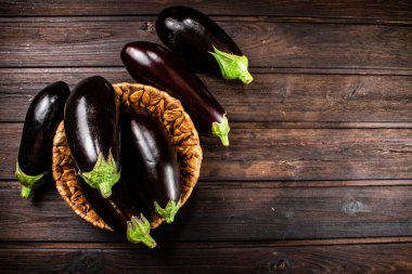 Ripe eggplant in a basket on the table. On a wooden background. High quality photo