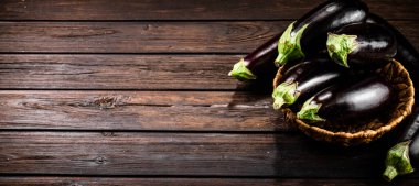 Ripe eggplant in a basket on the table. On a wooden background. High quality photo