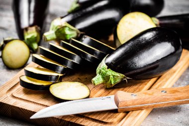 Cut into pieces of ripe eggplant on a wooden cutting board. On a gray background. High quality photo