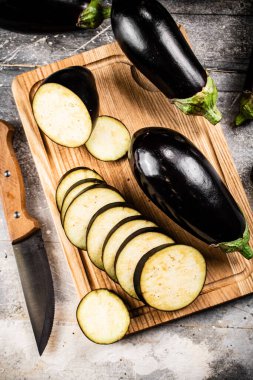 Cut into pieces of ripe eggplant on a wooden cutting board. On a gray background. High quality photo