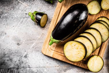 Cut into pieces of ripe eggplant on a wooden cutting board. On a gray background. High quality photo