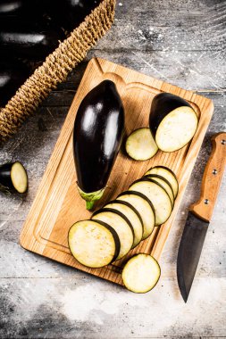 Cut into pieces of ripe eggplant on a wooden cutting board. On a gray background. High quality photo