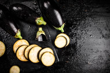 Pieces of ripe eggplant on a stone board. On a black background. High quality photo