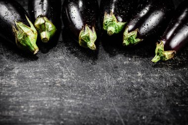 Fresh wet eggplant on the table. On a black background. High quality photo