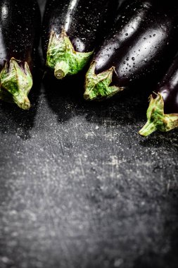 Fresh wet eggplant on the table. On a black background. High quality photo