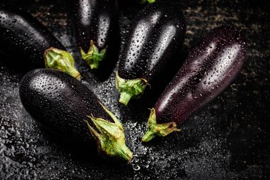 Fresh wet eggplant on the table. On a black background. High quality photo