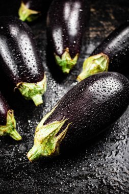 Fresh wet eggplant on the table. On a black background. High quality photo