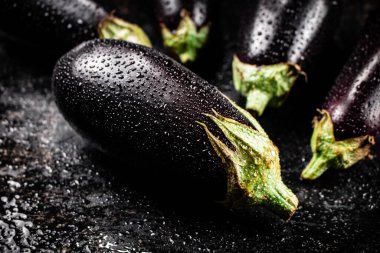 Fresh wet eggplant on the table. On a black background. High quality photo