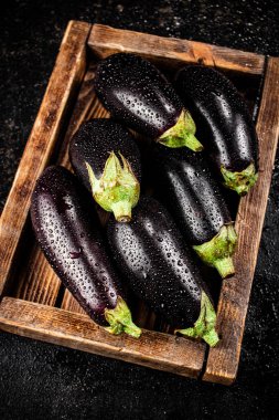 Ripe eggplant on a wooden tray. On a black background. High quality photo