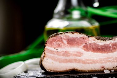 Delicious lard on a stone board with onions and spices. On a black background. High quality photo