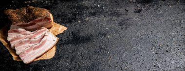 Fragrant pieces of pork ladr on paper. On a black background. High quality photo