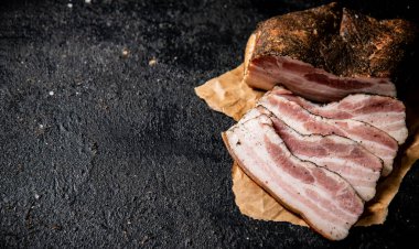 Fragrant pieces of pork ladr on paper. On a black background. High quality photo