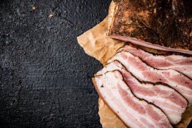 Fragrant pieces of pork ladr on paper. On a black background. High quality photo