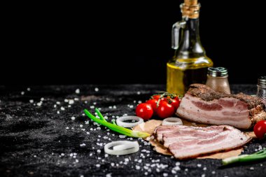 Pieces of lard on paper with onions and tomatoes. On a black background. High quality photo
