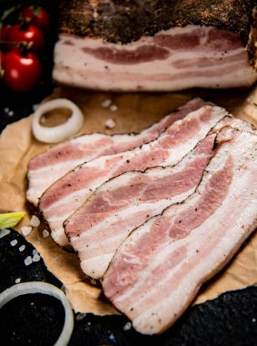 Sliced pork lard on paper with onion rings. On a black background. High quality photo