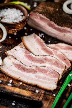 Chopped lard on a cutting board with green onions and spices. On a black background. High quality photo