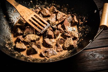 Cooked liver in a saucepan. On a wooden background. High quality photo