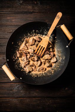 Cooked liver in a saucepan. On a wooden background. High quality photo