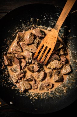Cooked liver in a saucepan. On a wooden background. High quality photo