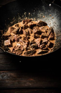 Cooked liver in a saucepan. On a wooden background. High quality photo