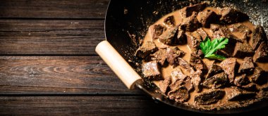 Cooked liver in a saucepan. On a wooden background. High quality photo