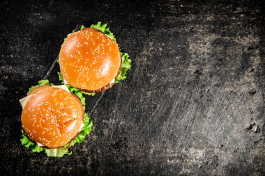 Masadaki taş bir tahtanın üzerinde bir hamburger. Siyah bir arka planda. Yüksek kalite fotoğraf