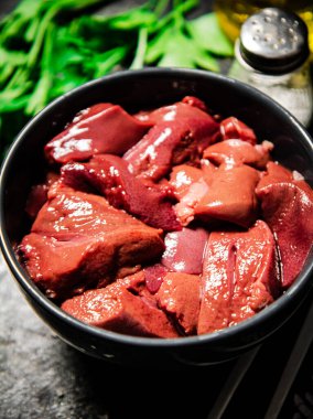 Sliced raw liver in a bowl. On a black background. High quality photo