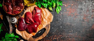 Pieces of raw liver with spices, oil and herbs. Against a dark background. High quality photo