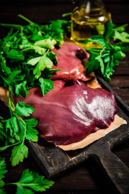 Raw liver on a cutting board on paper. On a wooden background. High quality photo