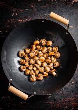 Small fried mushrooms in a frying pan. Against a dark background. High quality photo
