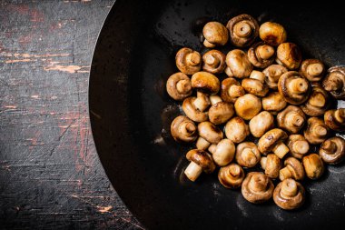 Small fried mushrooms in a frying pan. Against a dark background. High quality photo