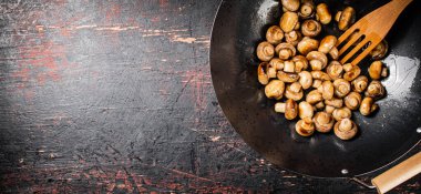 Small fried mushrooms in a frying pan. Against a dark background. High quality photo