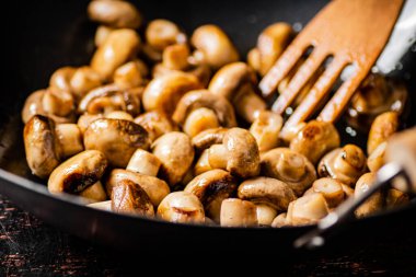 Mushrooms are fried in a frying pan. Macro background. High quality photo
