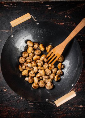 Small fried mushrooms in a frying pan. Against a dark background. High quality photo