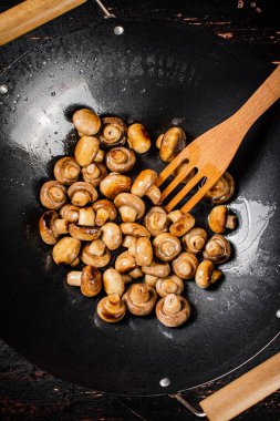 Small fried mushrooms in a frying pan. Against a dark background. High quality photo