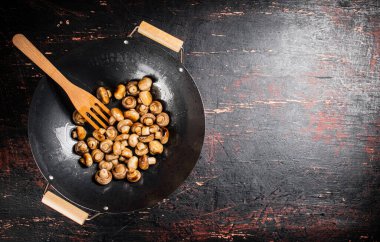 Small fried mushrooms in a frying pan. Against a dark background. High quality photo