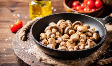 Frying pan with fried mushrooms on a wooden tray. On a wooden background. High quality photo