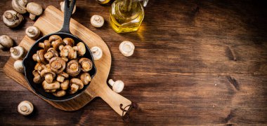 Fried mushrooms in a frying pan on a cutting board. On a wooden background. High quality photo