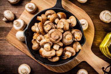 Fried mushrooms in a frying pan on a cutting board. On a wooden background. High quality photo