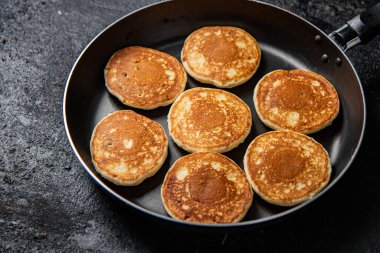 Homemade pancakes in a frying pan. On a black background. High quality photo