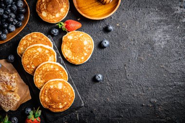 Pancakes on a stone board with fresh berries. On a black background. High quality photo